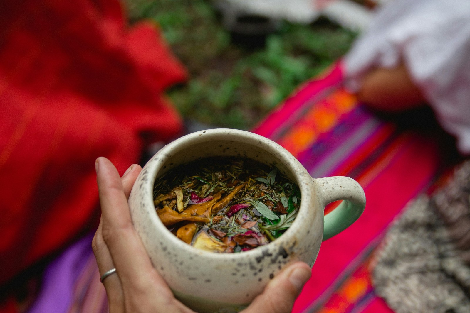 Hand holding a ceramic mug filled with herbal tea.