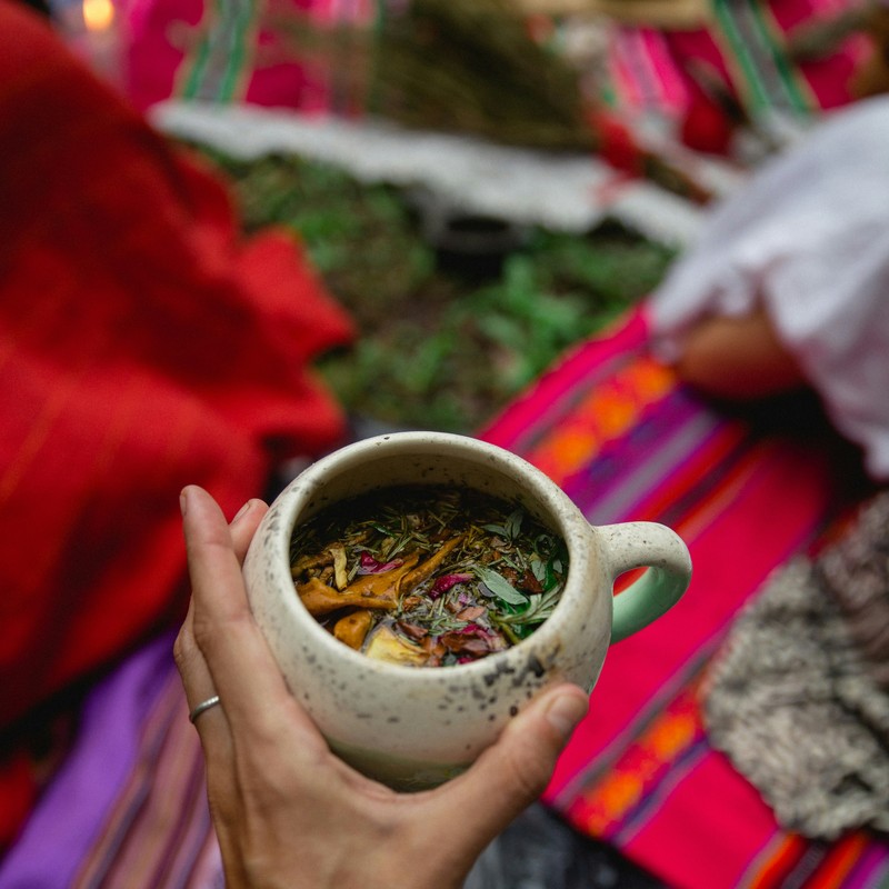 Hand holding a ceramic mug filled with herbal tea.